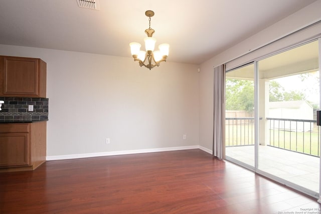 unfurnished dining area with dark wood finished floors, baseboards, a chandelier, and visible vents