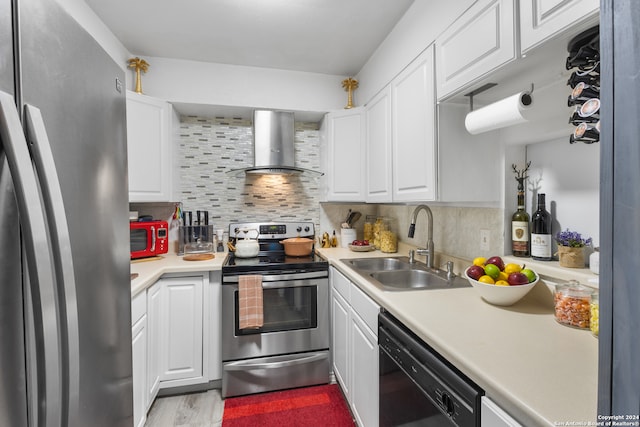 kitchen with light wood-type flooring, backsplash, stainless steel appliances, white cabinets, and wall chimney range hood