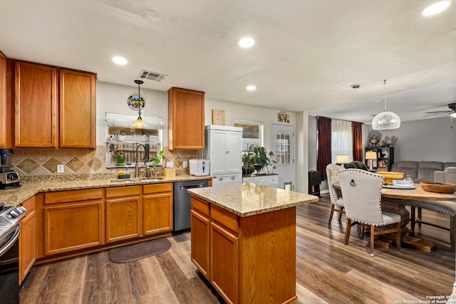 kitchen featuring light stone countertops, sink, stainless steel appliances, decorative light fixtures, and hardwood / wood-style flooring