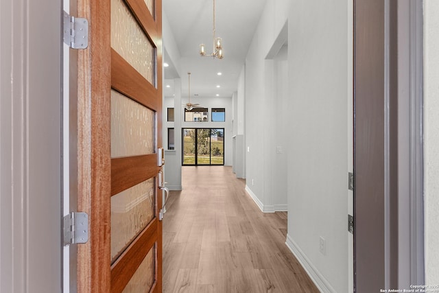 hall with recessed lighting, baseboards, a notable chandelier, and light wood-style flooring