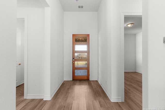 hallway with visible vents, baseboards, and light wood-style floors