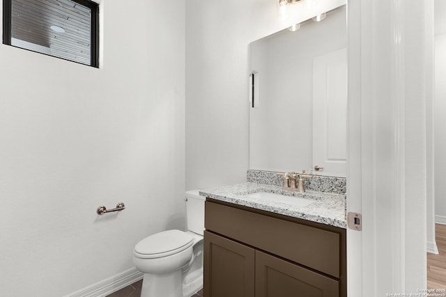 half bath with vanity, toilet, and baseboards