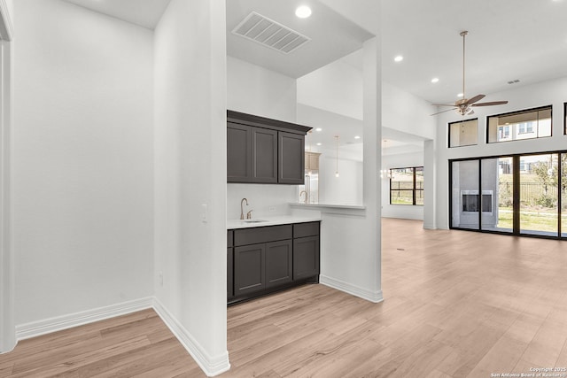 kitchen with visible vents, light wood-style flooring, a sink, light countertops, and open floor plan