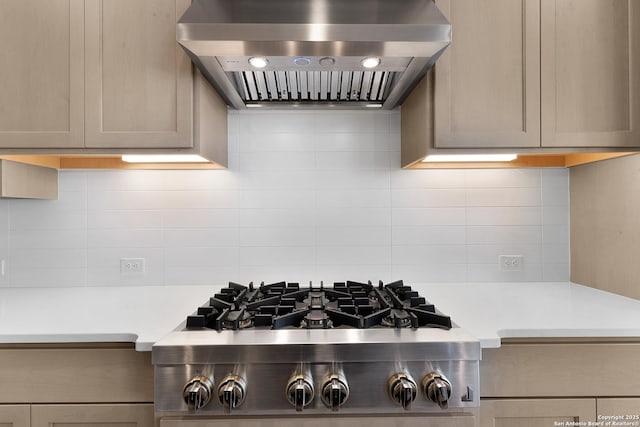 kitchen with light countertops, stainless steel gas stovetop, wall chimney exhaust hood, and backsplash