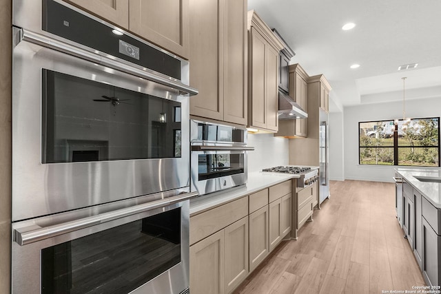 kitchen featuring under cabinet range hood, light countertops, recessed lighting, appliances with stainless steel finishes, and light wood-style flooring