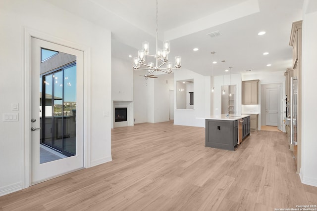 kitchen with visible vents, open floor plan, light countertops, light wood-type flooring, and a fireplace