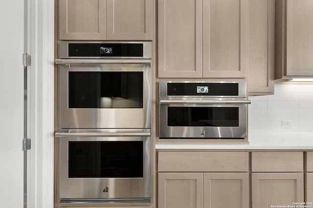 kitchen with stainless steel double oven, light countertops, and decorative backsplash