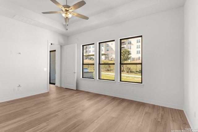 unfurnished room featuring visible vents, a raised ceiling, baseboards, and light wood finished floors