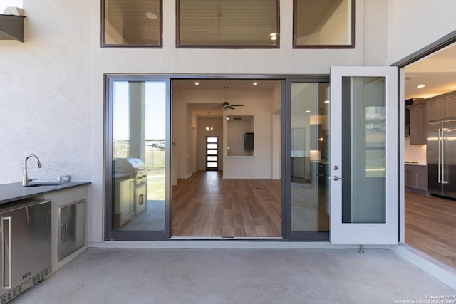 view of exterior entry featuring exterior kitchen, stucco siding, and a sink