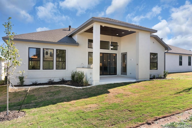 rear view of house with a yard, stucco siding, a patio, and roof with shingles