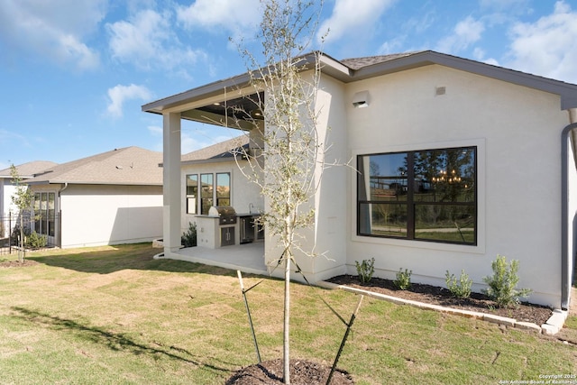 back of property featuring stucco siding, a patio, and a lawn