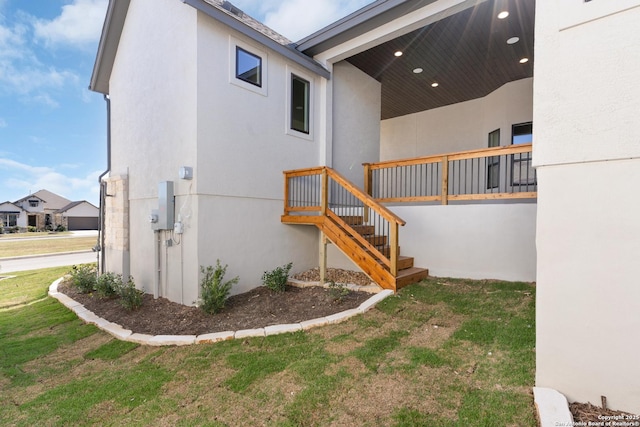 view of side of property featuring a lawn and stucco siding