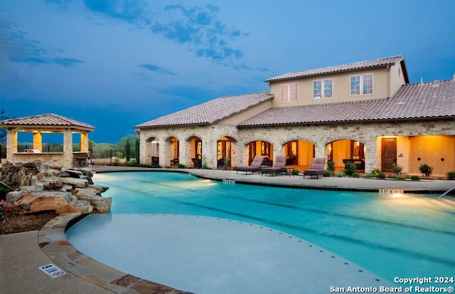 community pool with a gazebo and a patio