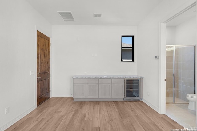 interior space with beverage cooler, visible vents, baseboards, and light wood-style floors