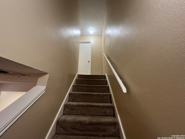 stairs featuring a textured ceiling