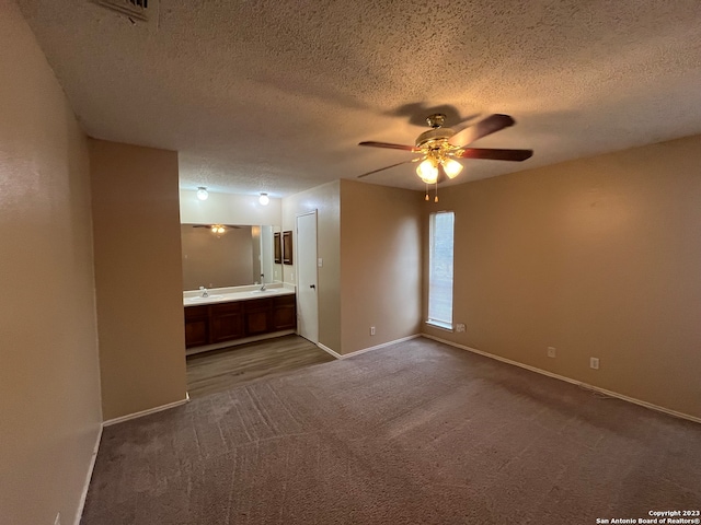 carpeted empty room with a textured ceiling, sink, and ceiling fan