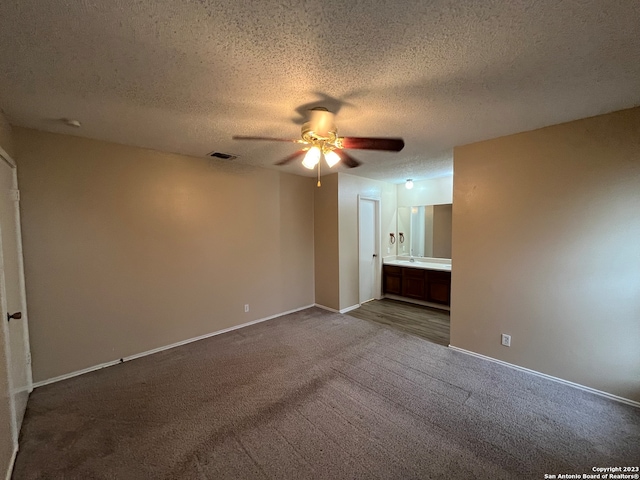 unfurnished bedroom with a textured ceiling, carpet, ceiling fan, and ensuite bathroom