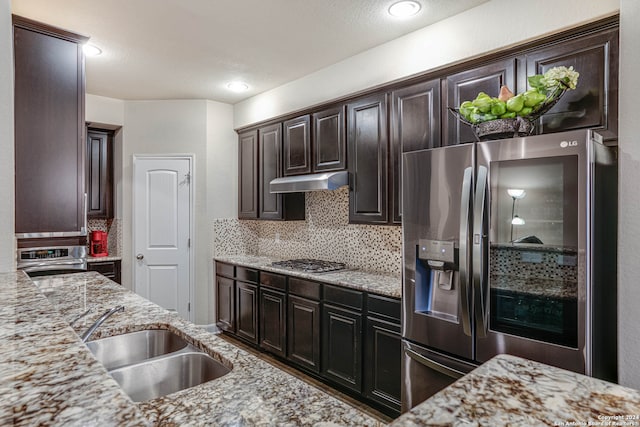 kitchen featuring light stone counters, appliances with stainless steel finishes, dark brown cabinets, and tasteful backsplash