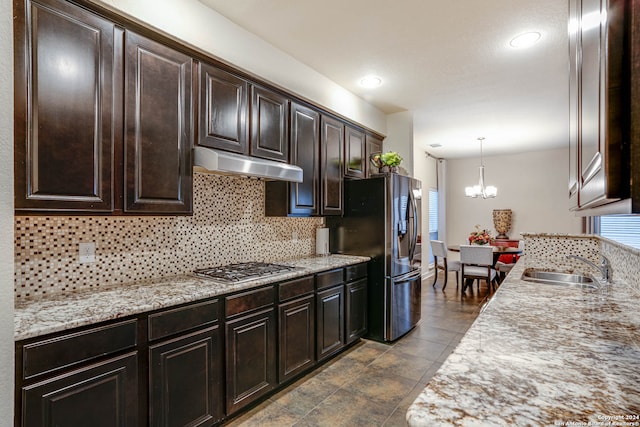 kitchen featuring pendant lighting, sink, a chandelier, stainless steel appliances, and decorative backsplash