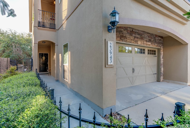 view of exterior entry featuring a balcony and a garage