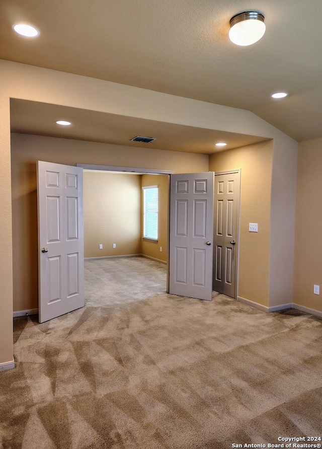 carpeted spare room featuring vaulted ceiling