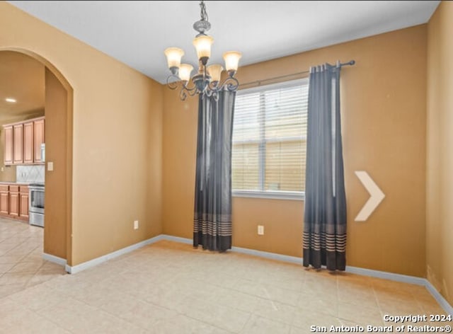 spare room featuring baseboards, arched walkways, an inviting chandelier, and light tile patterned flooring