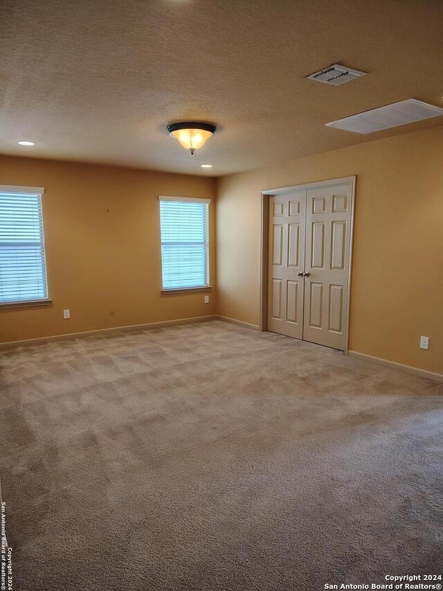 unfurnished room with a textured ceiling and carpet floors