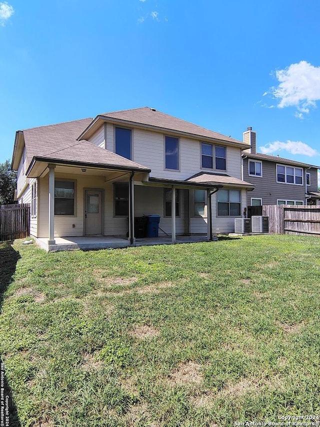 rear view of property with a lawn, cooling unit, and a patio