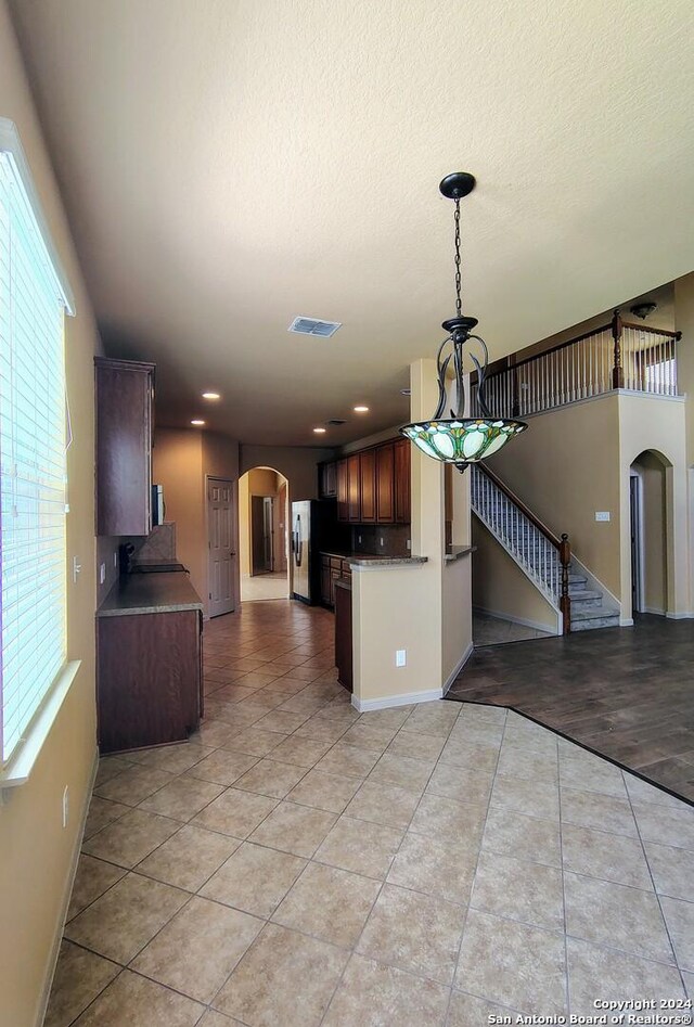 kitchen with kitchen peninsula, a textured ceiling, a towering ceiling, and light hardwood / wood-style flooring