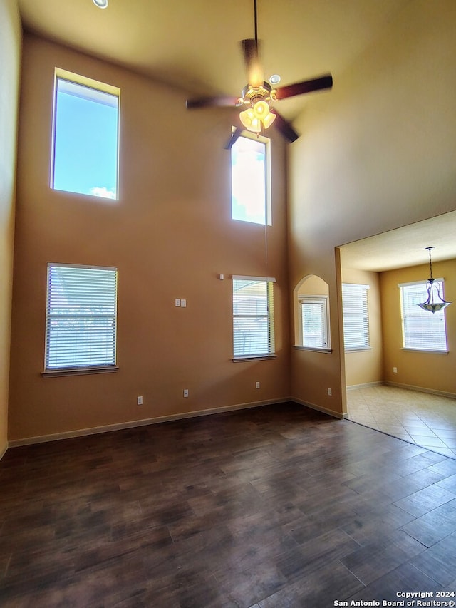 unfurnished living room featuring a towering ceiling, dark hardwood / wood-style floors, and ceiling fan