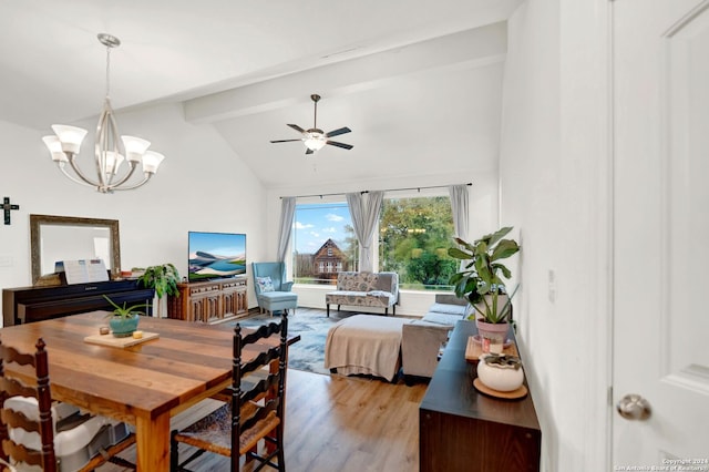 dining space featuring ceiling fan with notable chandelier, light wood-type flooring, and lofted ceiling with beams