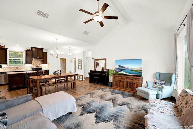 living room featuring ceiling fan with notable chandelier, light hardwood / wood-style floors, and vaulted ceiling with beams