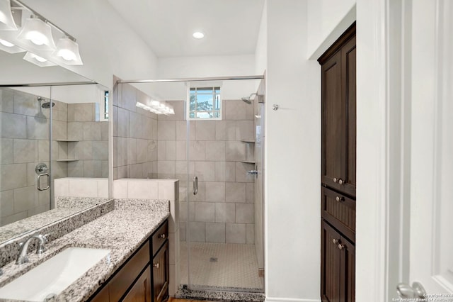 bathroom featuring a shower with shower door and vanity