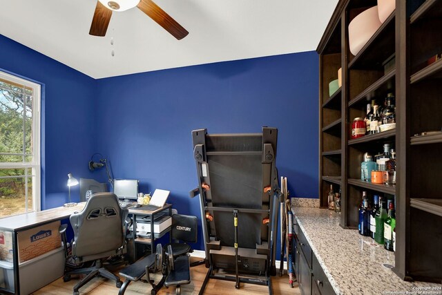 home office with light wood-type flooring and ceiling fan