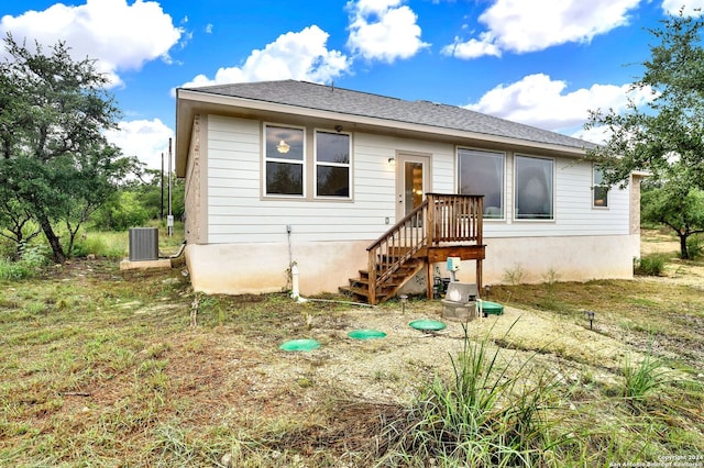 rear view of house featuring central AC and roof with shingles