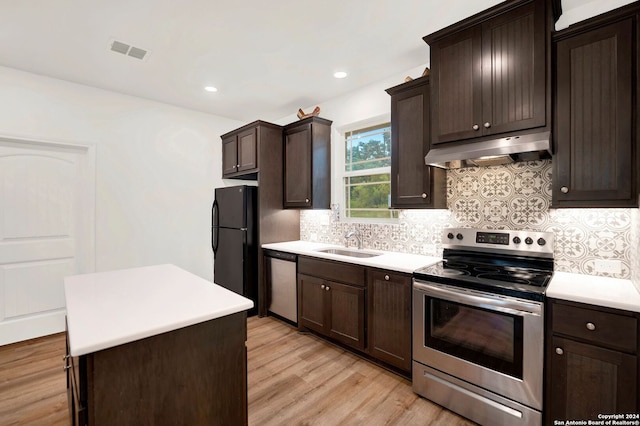 kitchen featuring light hardwood / wood-style flooring, stainless steel appliances, sink, dark brown cabinets, and decorative backsplash