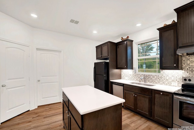 kitchen featuring dark brown cabinets, appliances with stainless steel finishes, a center island, sink, and light wood-type flooring