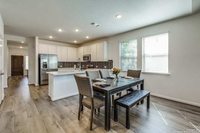 dining space featuring a textured ceiling, light hardwood / wood-style flooring, and sink