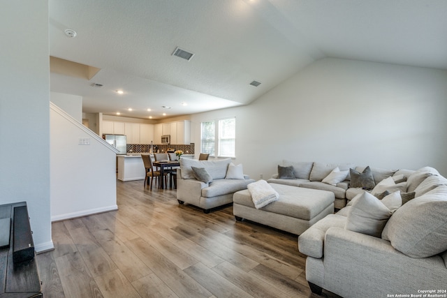 living room with vaulted ceiling and light hardwood / wood-style floors