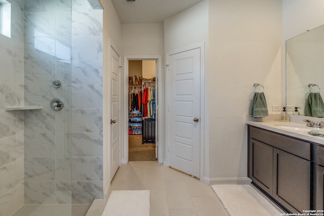 bathroom featuring vanity, a tile shower, and tile patterned floors