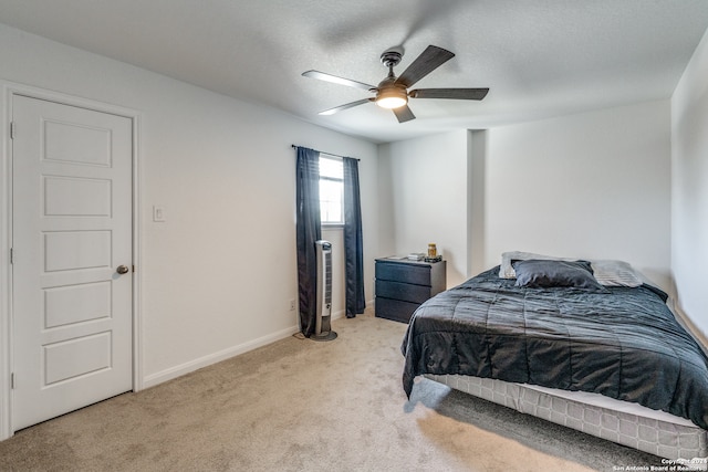 bedroom featuring a textured ceiling, light colored carpet, and ceiling fan