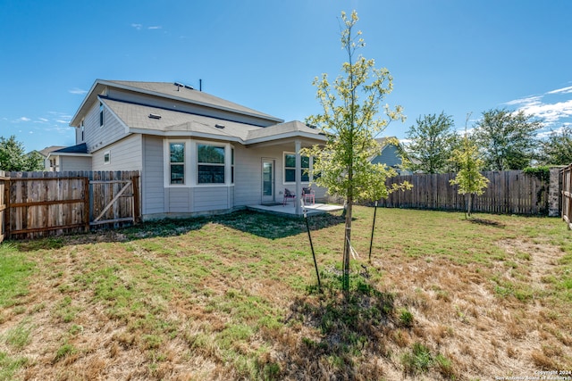 back of house with a yard and a patio