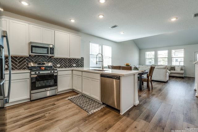 kitchen with stainless steel appliances, sink, hardwood / wood-style floors, and white cabinetry