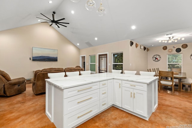 kitchen featuring ceiling fan with notable chandelier, lofted ceiling, light stone countertops, and white cabinets