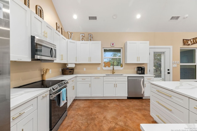 kitchen featuring white cabinetry, appliances with stainless steel finishes, lofted ceiling, and light stone countertops