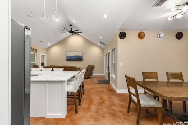 kitchen featuring vaulted ceiling, light stone countertops, hanging light fixtures, stainless steel refrigerator, and light colored carpet