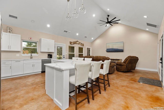 kitchen with a kitchen bar, a kitchen island, light stone countertops, ceiling fan, and stainless steel dishwasher