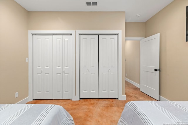 bedroom featuring two closets and light colored carpet