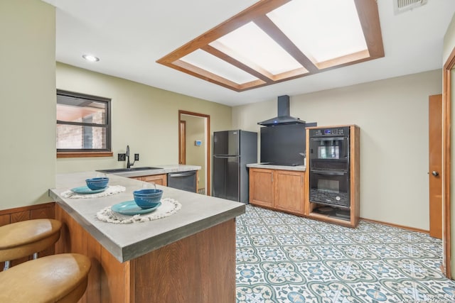 kitchen with a breakfast bar, black appliances, sink, exhaust hood, and kitchen peninsula