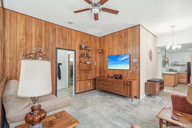 living room with sink, wooden walls, and ceiling fan with notable chandelier